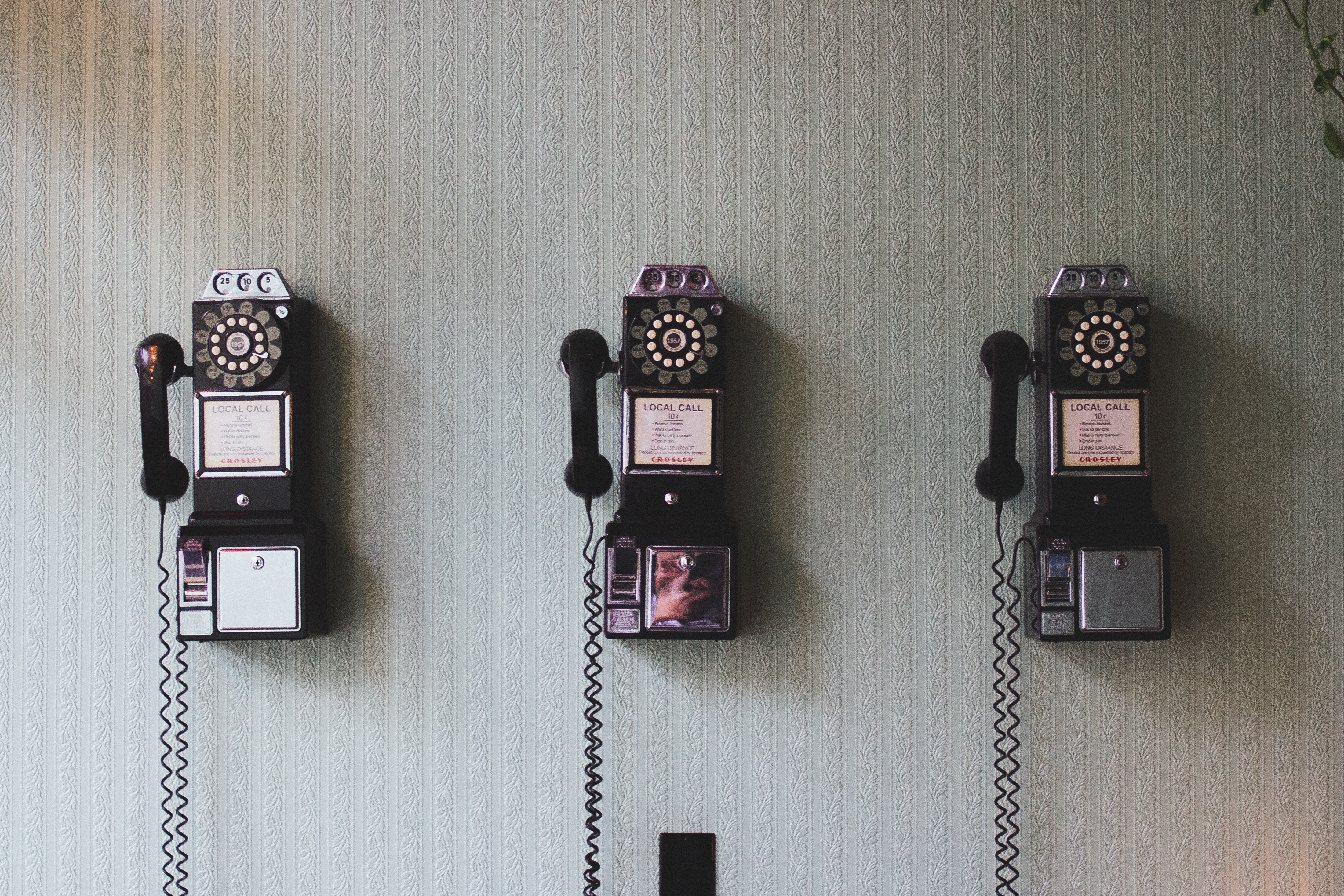 Old fashioned telephones lined up on a wall 